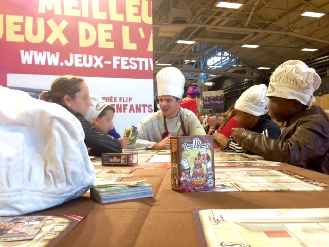 Emmanuel Guignard en animation du jeu de société Pièces Montées sur la Kidexpo, valorisant le Trophée FLIP éditeurs qu'il a remporté en 2014